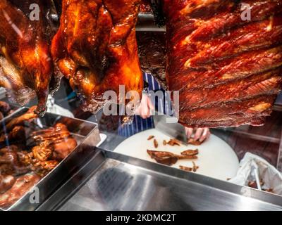 CRISPY DUCK CHINATOWN LONDON window display of specialty cooked crispy duck air drying and chef preparing his Chinese specialty crispy duck meal at night, in Soho Chinatown restaurant London UK Stock Photo