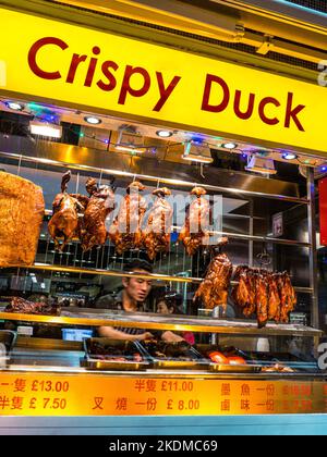 CRISPY DUCK CHINATOWN LONDON window display of specialty cooked crispy duck air drying and chef arranging his Chinese food displays at night, in Soho Chinatown restaurant London UK Stock Photo