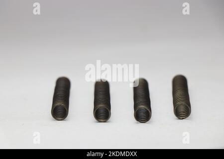 Four steel compression coil springs with same surface finish with a view of its bottom part isolated on white background Stock Photo