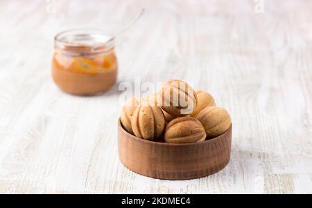 Traditional Russian homemade sweet pastries, shortbread nuts with boiled condensed milk, sprinkled with powdered sugar in a wooden bowl on a wooden ba Stock Photo