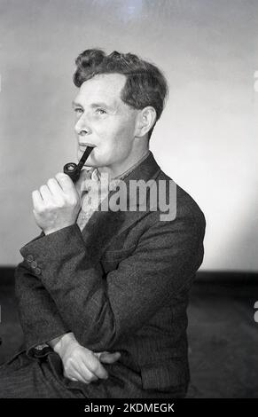 1960s, historical, a man wearing a herring bone tweed suit and rolled-neck sweater, smoking his pipe, England, UK. Stock Photo