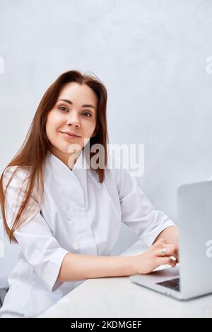 female doctor in white medical uniform using laptop Stock Photo