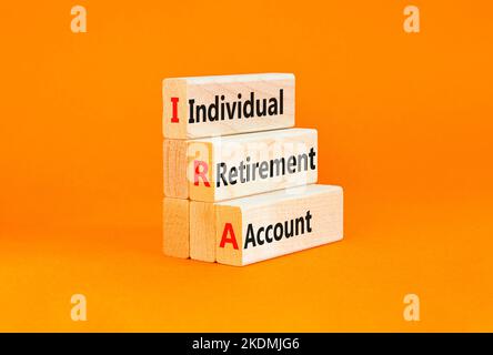 IRA individual retirement account symbol. Concept words IRA individual retirement account on wooden blocks on beautiful orange background. Business IR Stock Photo