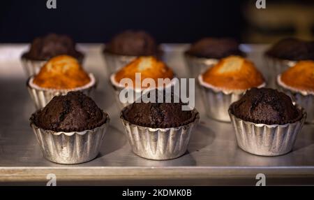 Freshly baked muffins in metal molds close-ups in a bakery. Stock Photo