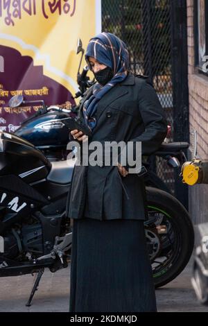 A muslim woman in a hijab reads from her cell phone. In Jackson Heights, Queens, New York. Stock Photo