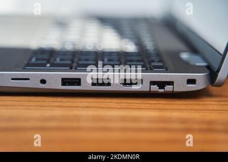 Side view of a gray laptop keyboard on a wooden table. USB ports on a laptop Stock Photo