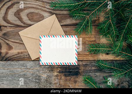 Blank postcard, envelope and fir branches on a wooden background, flat lay. Stock Photo