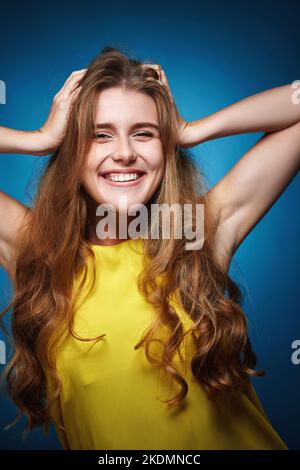 happy woman with strong healthy curly hair dancing on blue background Stock Photo