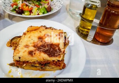 Greek food moussaka on a local restaurant dining table with olive oil at the background. Stock Photo