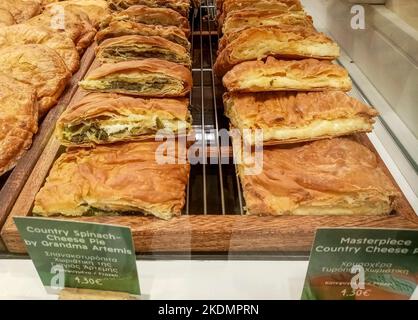 Freshly baked Greek spinach pie and cheese pie lined up for sale in a Greece local food shop. Stock Photo
