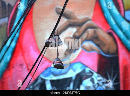 A pair of sneakers hanging on a power line in front of a mural on the former Luzerne County Community College building.Wilkes Barre Pennsylvania. USA. Stock Photo