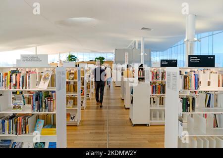 Modern library interior with book shelves and walking readers in Helsinki, Finland Stock Photo