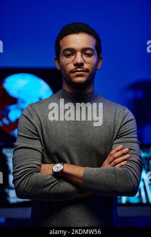 Young confident software developer or IT support manager in grey casual pullover crossing arms by chest while standing in front of camera Stock Photo