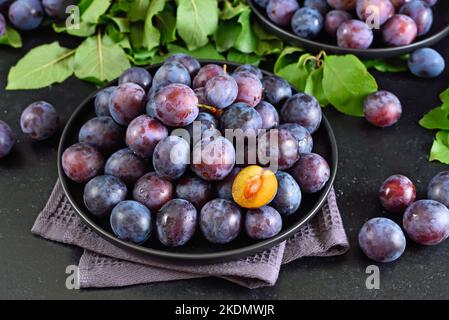 Fresh plums on plate over dark stone background Stock Photo