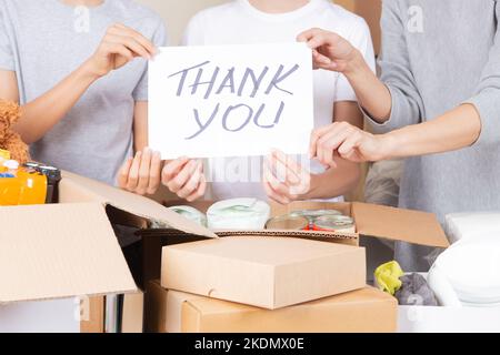 Thank you for donation. Volunteers collecting donations for charity. Teenagers and woman hands holding paper sheet with message Thank you over Stock Photo