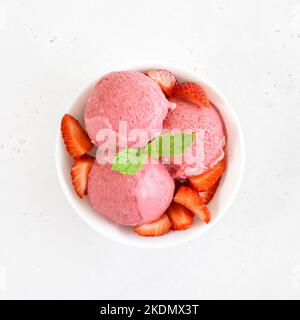 Strawberry ice cream in white bowl on stone background. Top view, flat lay Stock Photo