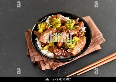 Beef and broccoli stir fry with rice in bowl Stock Photo