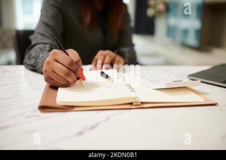 Person writing notes in a planner next to a laptop and coffee Stock ...