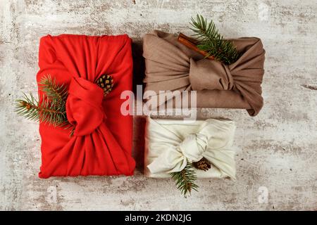 Christmas eco friendly gift wrapping in traditional Japanese Furoshiki style. Environmental present wrapping concept. Presents with green fir, pine co Stock Photo