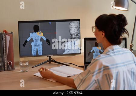 Back view at young female designer building digital 3D models and using computers at workplace Stock Photo