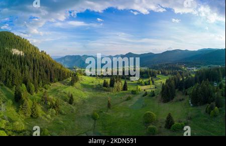 Valley of Balkan mountains is covered with fog, sunny clouds and evergreen spruce forests. Village Pamporovo in intermountain. Panorama, top view Stock Photo