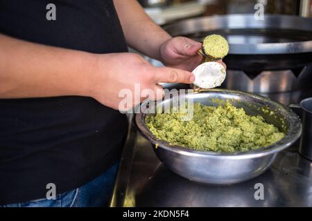 Man Hands with Tool Form Falafel Balls From a Stainless Steel Bowl on a Countertop in Close-Up Shot Stock Photo