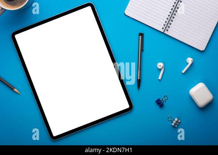 Notebook and Tablet Computer on Blue Desk or background laying flat on Creative workplace as mockup or Template with empty or blank page or screen Stock Photo