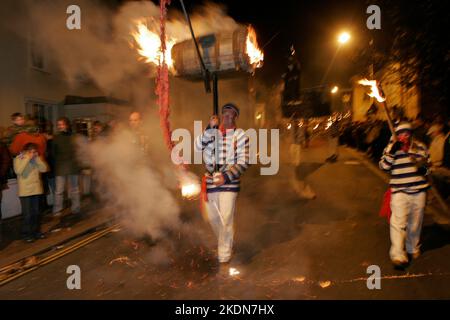 Jason Winter, Captain of Tar Barrels for Borough, carries a flaming barrel with a string of burning fire-crackers in the main procession of the evening. Stock Photo