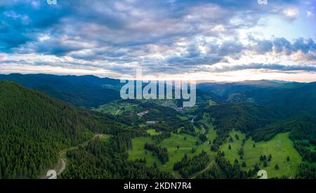 Valley of Balkan mountains is covered with fog, sunny clouds and evergreen spruce forests. Village Pamporovo in intermountain. Panorama, top view Stock Photo