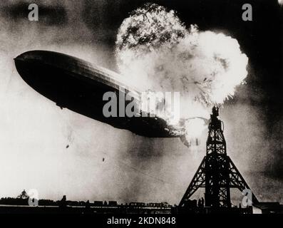 ADVANCE FOR SUNDAY AUG. 22--FILE--This photo, taken during the initial explosion of the Hindenburg, shows the 804-foot German zeppelin just before subsequent explosions sent the ship crashing to the ground at Lakehurst Naval Air Station in Lakehurst, N.J., May 6, 1937. The roaring flames silhouette two men, at right atop the mooring mast, dangerously close to the blasts. The scene stimulated NBC radio broadcaster Herbert Morrison to give a memorable and highly emotion account of the disaster. (AP Photo/Philadelphia Public Ledger, HO) The Zeppelin LZ 129 Hindenburg catching fire on May 6, 1937 Stock Photo