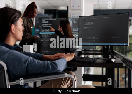 Asian programmer with physical disability typing html code on computer, working with cloud computing terminal window. Web developer in wheelchair writing ai algorithm in it software company. Stock Photo