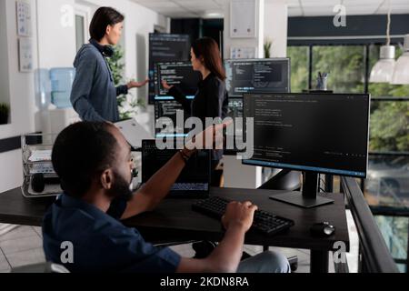 African american web developer in wheelchair looking at programming language, typing script on computer, using big data and firewall server. Engineer with physical impairment in big data office Stock Photo
