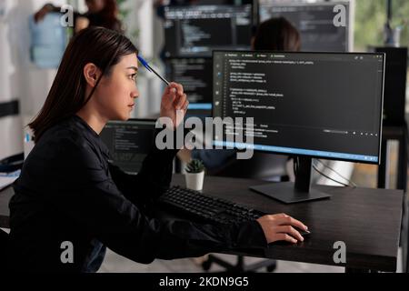 Pensive programmer thinking at ideas trying to write code and create new interface in data room. Web developer programming server database in busy artificial intelligence developing agency. Stock Photo