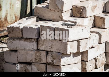 Building materials on site. Construction nails on stack of white bricks. Pile of blocks for construction. Stock Photo