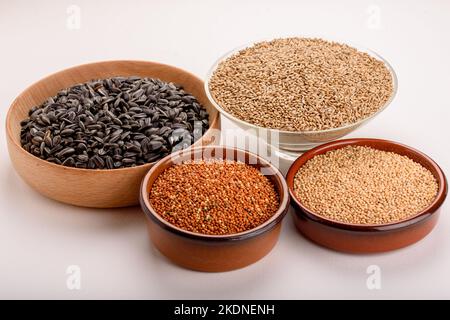 Dried grains bird food. Red millet grain, yellow millet grain, black sunflower seeds and canary grass seeds in pots. Stock Photo