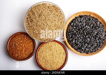 Dried grains bird food. Red millet grain, yellow millet grain, black sunflower seeds and canary grass seeds in pots. Stock Photo