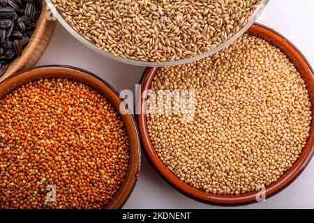 Dried grains bird food. Red millet grain, yellow millet grain, black sunflower seeds and canary grass seeds in pots. Stock Photo