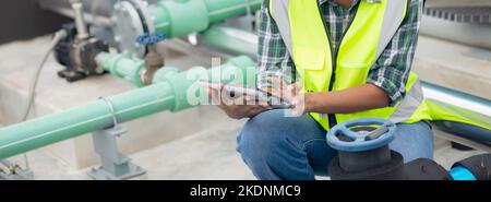 Young woman engineer examining pipeline and looking digital tablet with professional in the factory, mechanic or technician inspector plumber valve, o Stock Photo