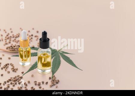 Legalized marijuana concept features with CBD oil extract from marihuana in glass bottle with dropper lid, piles of hemp seeds on empty background Stock Photo