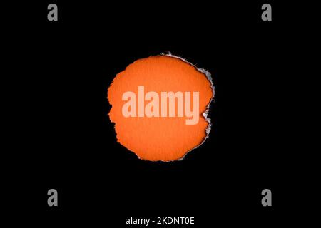 Torn black hole on orange paper background. As template for text or advertisement. Stock Photo