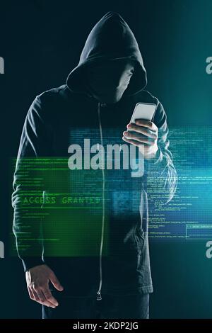 Hacking computers is so last year. an unidentifiable computer hacker using a smartphone while standing against a dark background. Stock Photo