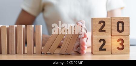 Hand stop falling blocks with 2023 year. Risk Management, recession, business financial, Resolution, strategy, goal, New Year planning and inflation e Stock Photo