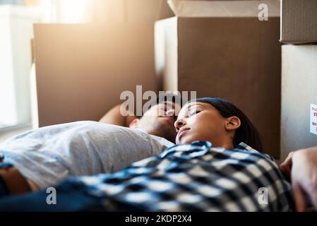 Breaking in their new floor. a happy young couple resting on the floor while moving into their new house. Stock Photo