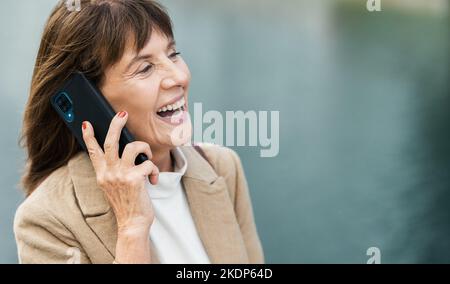 Business woman, communication and phone call in city, street or outdoors. Conversation, travel and mature female from Canada on 5g smartphone Stock Photo
