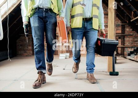 Construction, team and legs of engineers walking on the building site for home renovation project. People, construction worker teamwork and feet of Stock Photo