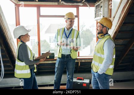 Teamwork, planning and engineers talking at construction site for repairs, maintenance or renovation. Tablet, clipboard and collaboration of Stock Photo