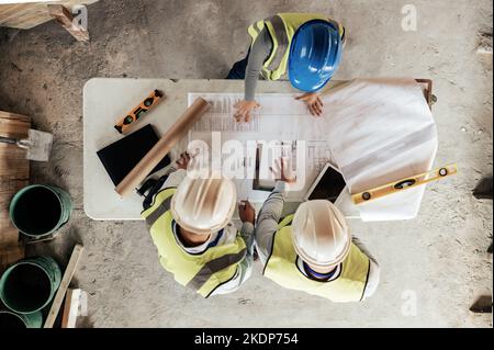 Architect, construction and blueprint with an engineer and designer team working on a building site from above. Meeting, planning and architecture Stock Photo
