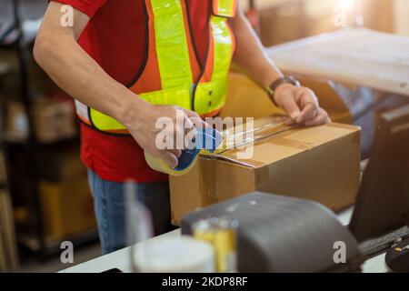 staff worker tape packing seal products box prepare for shipping delivery to online order customer. Stock Photo
