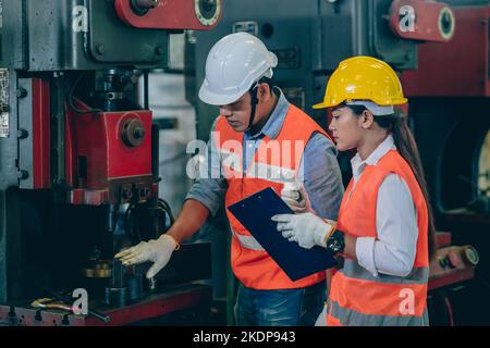 engineer male training and check machine with woman worker team in metal industry factory Stock Photo