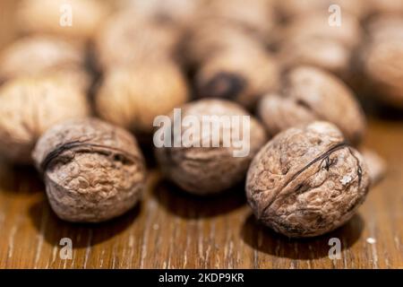 Heap of unpeeled walnuts on wooden table Stock Photo
